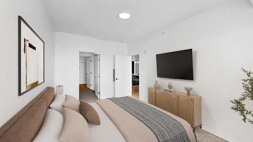 A modern bedroom with a large bed and a flat screen TV on the wall.