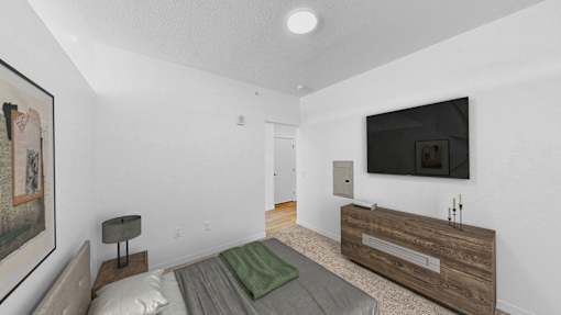 A modern bedroom with a bed, a nightstand, and a television.