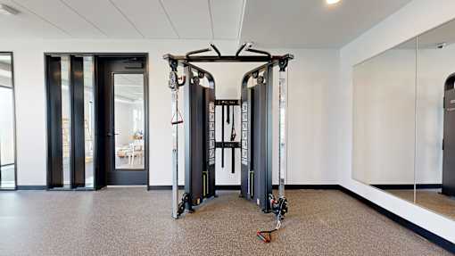 A gym room with a squat rack and a mirror.