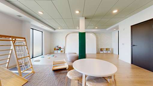 A white table is in the middle of a room with a green stripe on the wall.