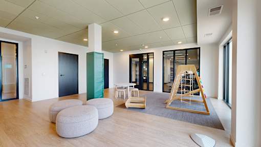A room with a wooden floor and a white wall with a black door.