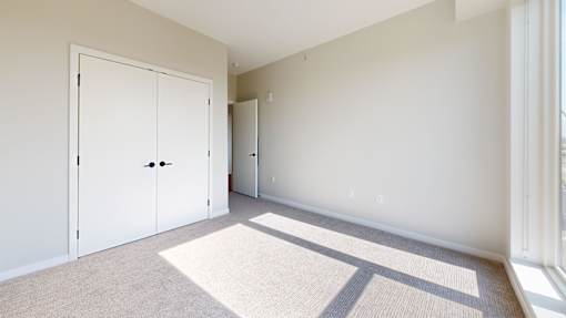 A room with a white door and a carpet on the floor.