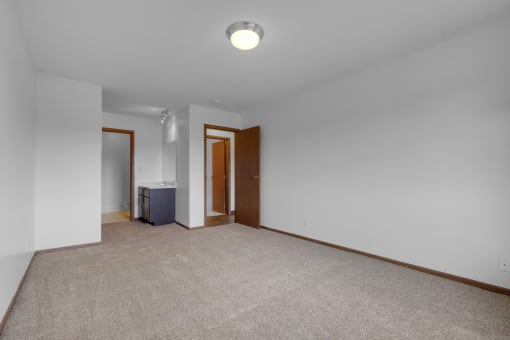 a bedroom with white walls and a beige carpet