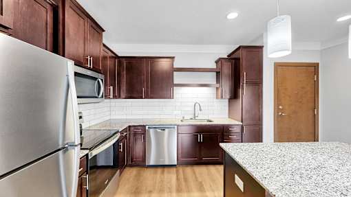 A kitchen with a refrigerator, microwave, and sink.