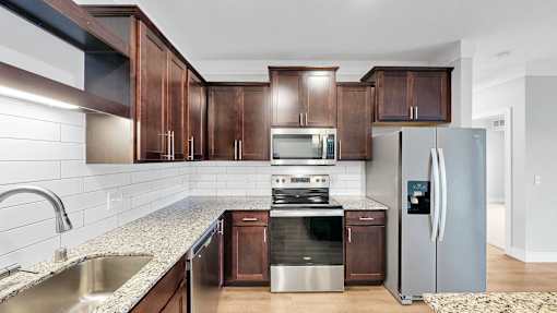 A kitchen with a refrigerator, sink, and stove.