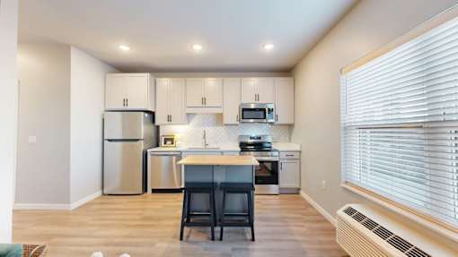A kitchen with a refrigerator, microwave, oven, and sink.