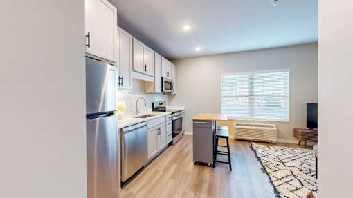 A modern kitchen with stainless steel appliances and wooden flooring.