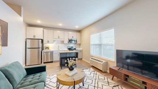 A modern kitchen with a green sofa and a coffee table in the foreground.