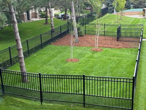 a black wrought iron fence surrounds a park with trees
