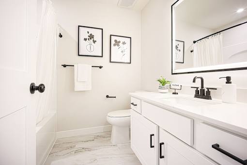 A white bathroom with a toilet, sink, and mirror.