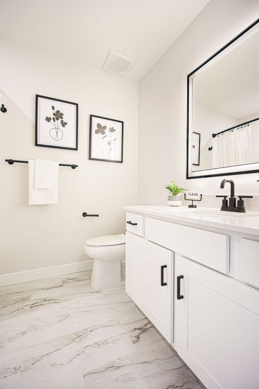 a white bathroom with a large mirror and a toilet