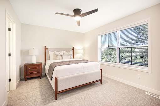 A bedroom with a bed, nightstand, and window.
