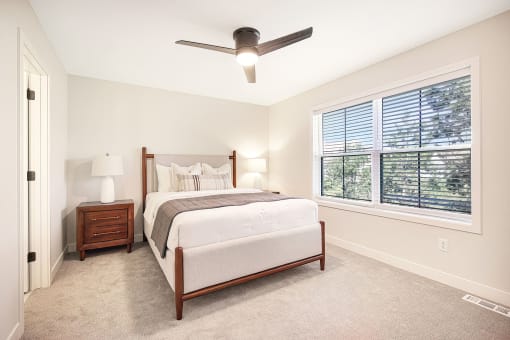a bedroom with a large window and a ceiling fan