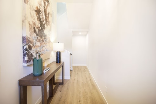 a long hallway with a table and a painting on the wall