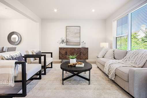 A living room with a grey couch, a coffee table, and a painting on the wall.