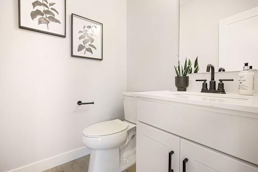 A white toilet sits in a bathroom next to a sink.