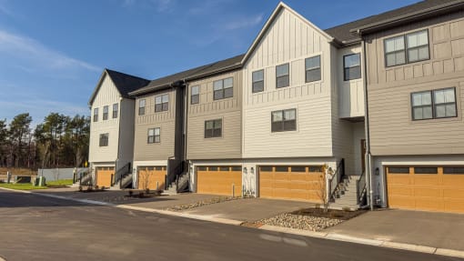 a row of apartment buildings with wooden garage doors