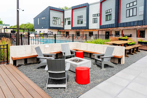 a seating area with tables and chairs in front of a row of buildings