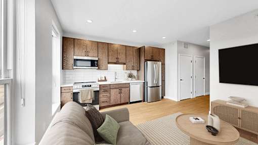 A modern kitchen with wooden cabinets and a grey sofa.