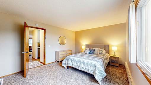 A bedroom with a bed, nightstand, and mirror.
