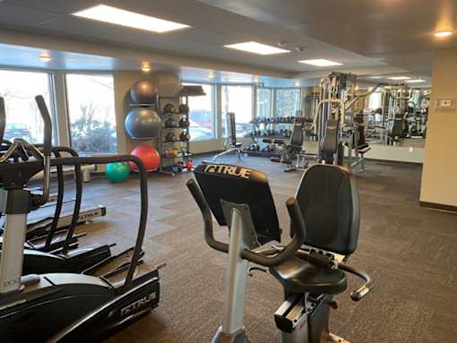 Fitness center with large windows and mirrors at Aspenwood Apartments, Eagan, MN