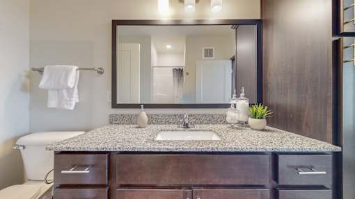 A bathroom with a granite countertop and a large mirror. at Lake Jonathan Flats, Chaska, MN, 55318