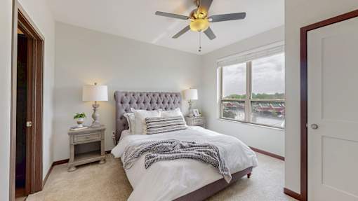 A bedroom with a large bed and a ceiling fan. at Lake Jonathan Flats, Chaska, MN, 55318