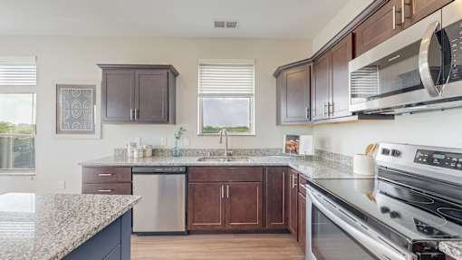 A kitchen with a granite countertop and stainless steel appliances. at Lake Jonathan Flats, Chaska, Minnesota