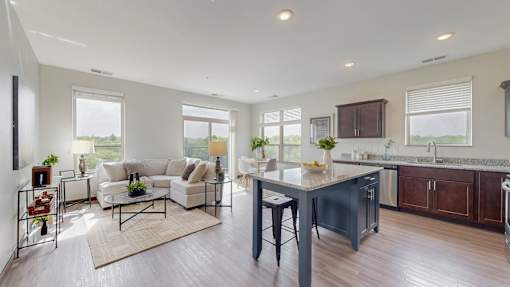 A modern kitchen and living room with a large island and dark wood floors. at Lake Jonathan Flats, Chaska