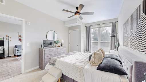 A bedroom with a large bed and a ceiling fan.