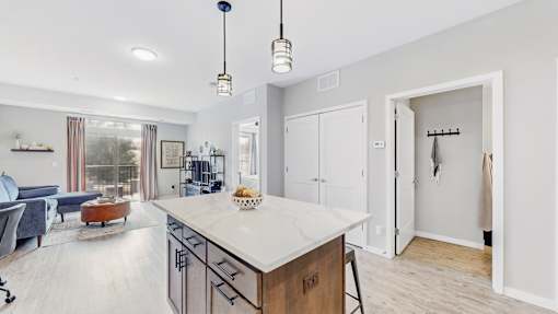 A modern kitchen with a large island and a view of the living room.