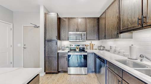 A modern kitchen with dark wood cabinets and stainless steel appliances.