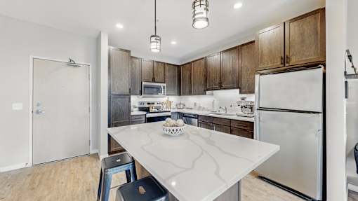 A kitchen with a white island and wooden cabinets.