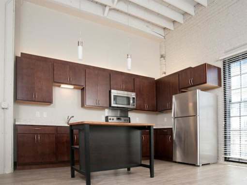 A kitchen with brown cabinets and a black island.