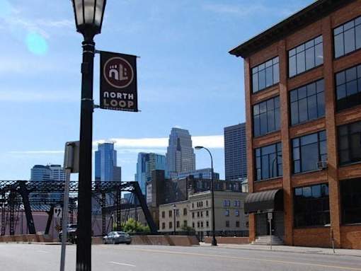 A street sign for the North Loop stands in front of a city skyline.