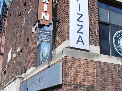 A brick building with a sign that says "RINZA" and "For Lease" on it.
