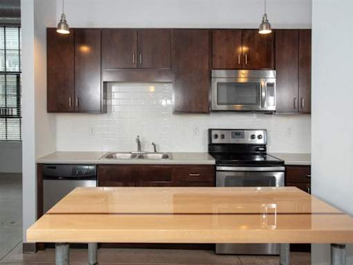 A kitchen with a wooden table and stainless steel appliances.at Gurley Lofts, Minneapolis