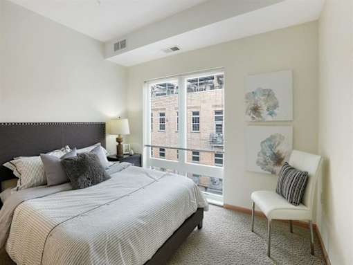 A bedroom with a large bed and a chair by the window.at Third North Apartments, Minneapolis, MN