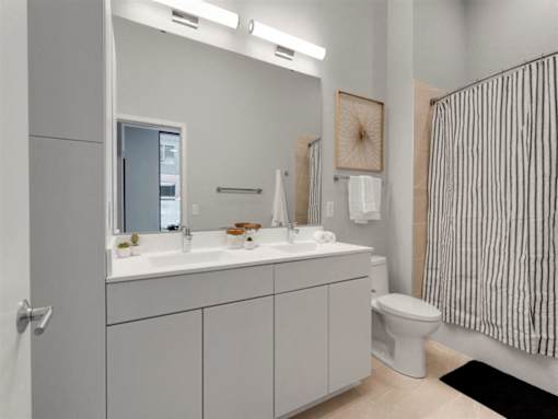 A bathroom with a white toilet, sink, and striped shower curtain.at Viridium Apartments, Minnesota, 55401