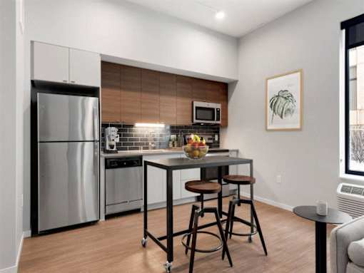A kitchen with a refrigerator, stove, and bar stools.at Viridium Apartments, Minnesota, 55401