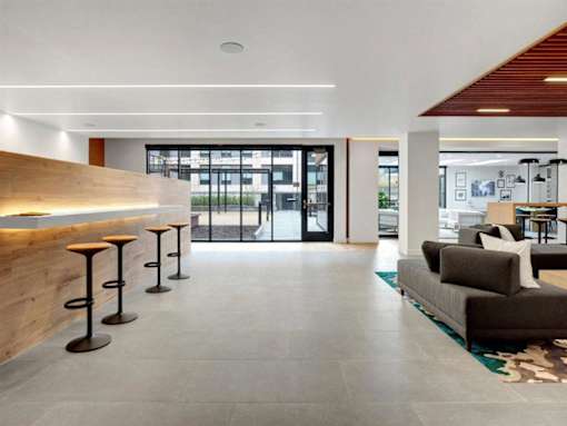 A modern living room with a couch, a table, and a bar with stools.at Viridium Apartments, Minneapolis 