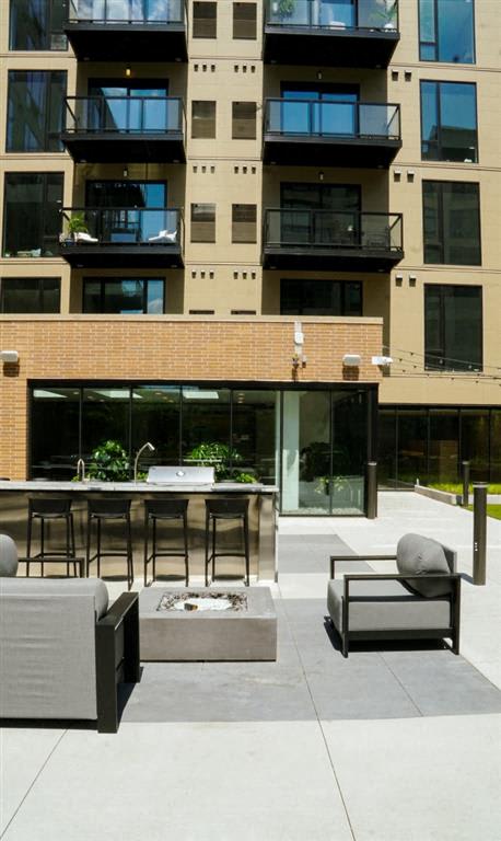 A patio with a table and chairs is in front of a building.at Viridium Apartments, Minnesota 