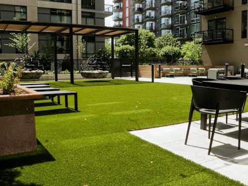 A patio with a table and chairs is surrounded by a grassy area and buildings.at Viridium Apartments, Minneapolis, MN 