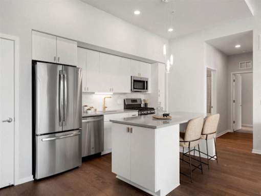 A modern kitchen with a stainless steel refrigerator and white cabinets.at Viridium Apartments, Minneapolis, MN 55401 