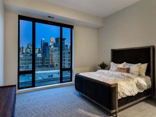A bedroom with a large bed and a view of the city.at Viridium Apartments, Minnesota, 55401