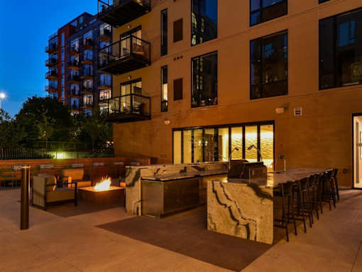 A patio area with a fire pit and seating area in front of a building.at Viridium Apartments, Minnesota 