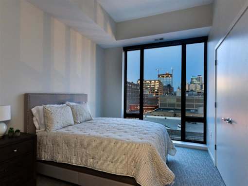 A bedroom with a large bed and a view of the city.at Viridium Apartments, Minnesota 