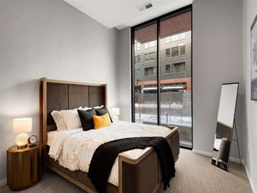 A bedroom with a large bed and a large window.at Viridium Apartments, Minneapolis, 55401 