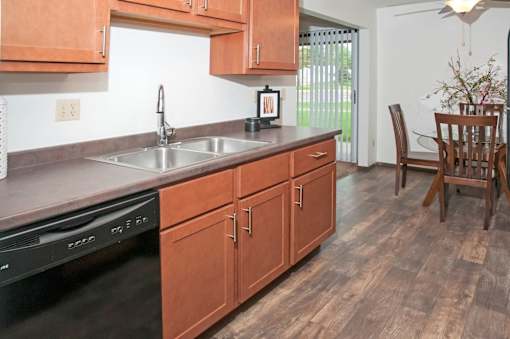 A kitchen with wooden cabinets and a black dishwasher.