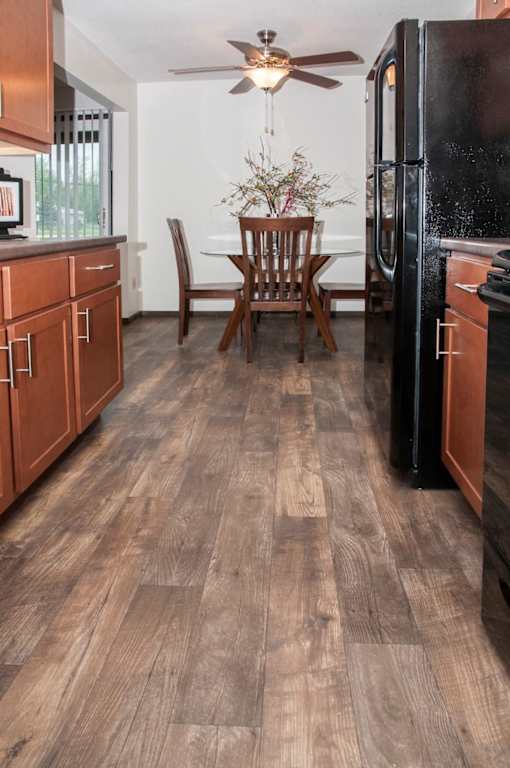 A kitchen with a wooden floor and a black refrigerator.